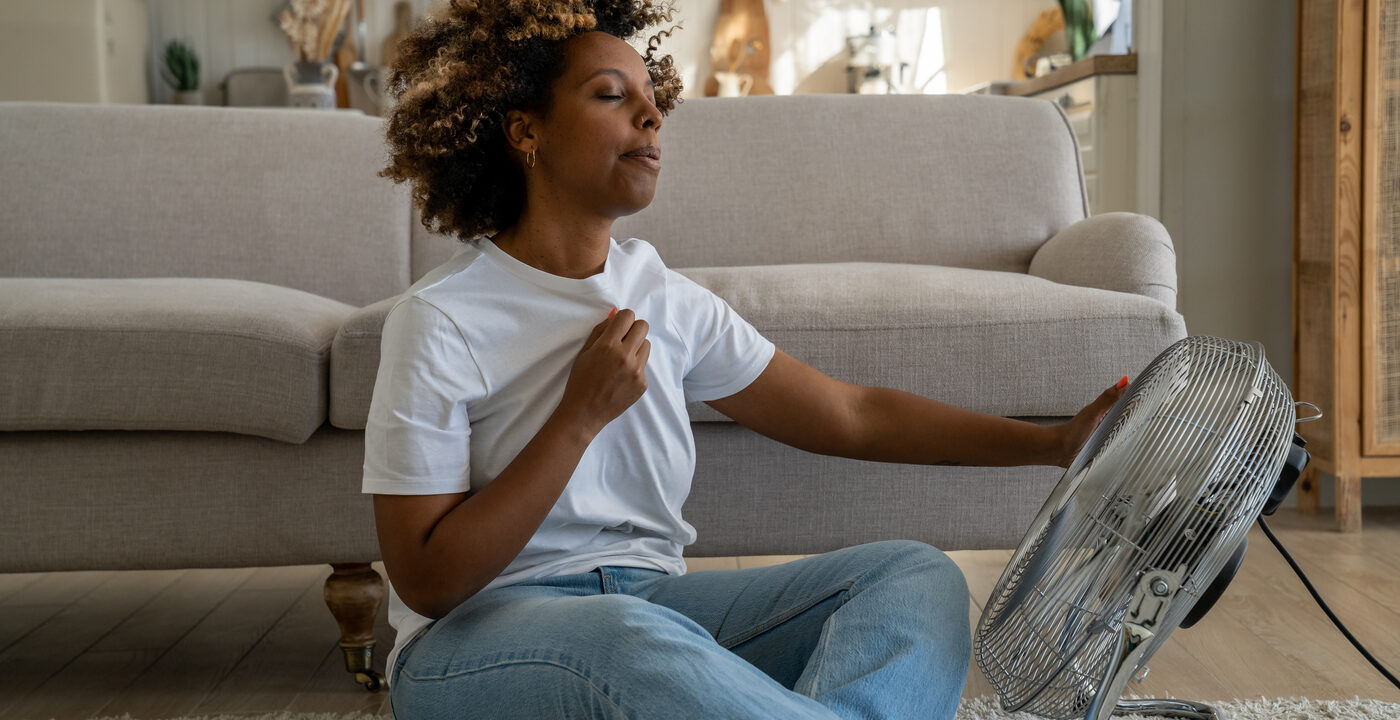 Woman sitting on the floor in front of a fan.