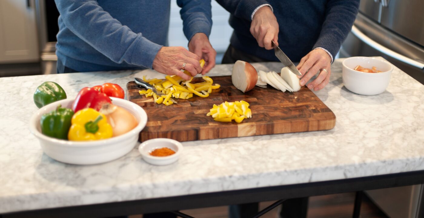 Two men in a kitchen chopping vegetables