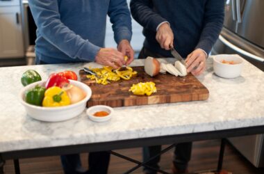 Two men in a kitchen chopping vegetables