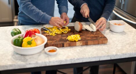Two men in a kitchen chopping vegetables