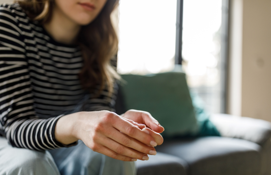 Woman sitting on a couch and cracking her knuckles
