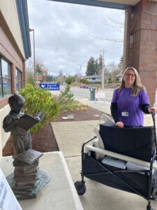 Woman stands in front of Eatonville Public Library with a wagon full of supplies