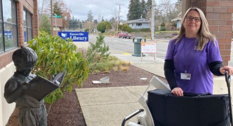 Woman stands in front of Eatonville Public Library with a wagon full of supplies
