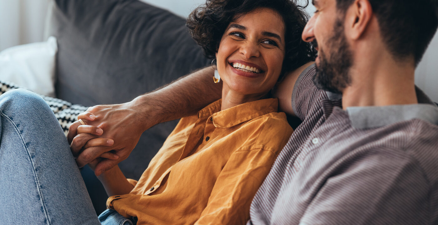 Woman smiling at man sitting on couch