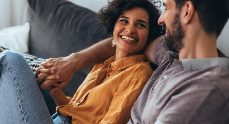 Woman smiling at man sitting on couch