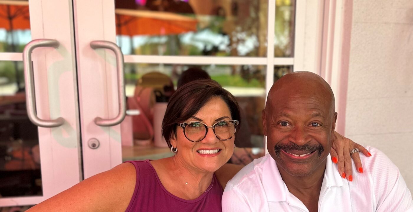 Woman and man smile for a photo in front of French doors