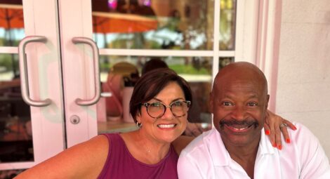 Woman and man smile for a photo in front of French doors