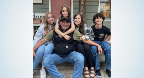Man sitting on steps with his four children