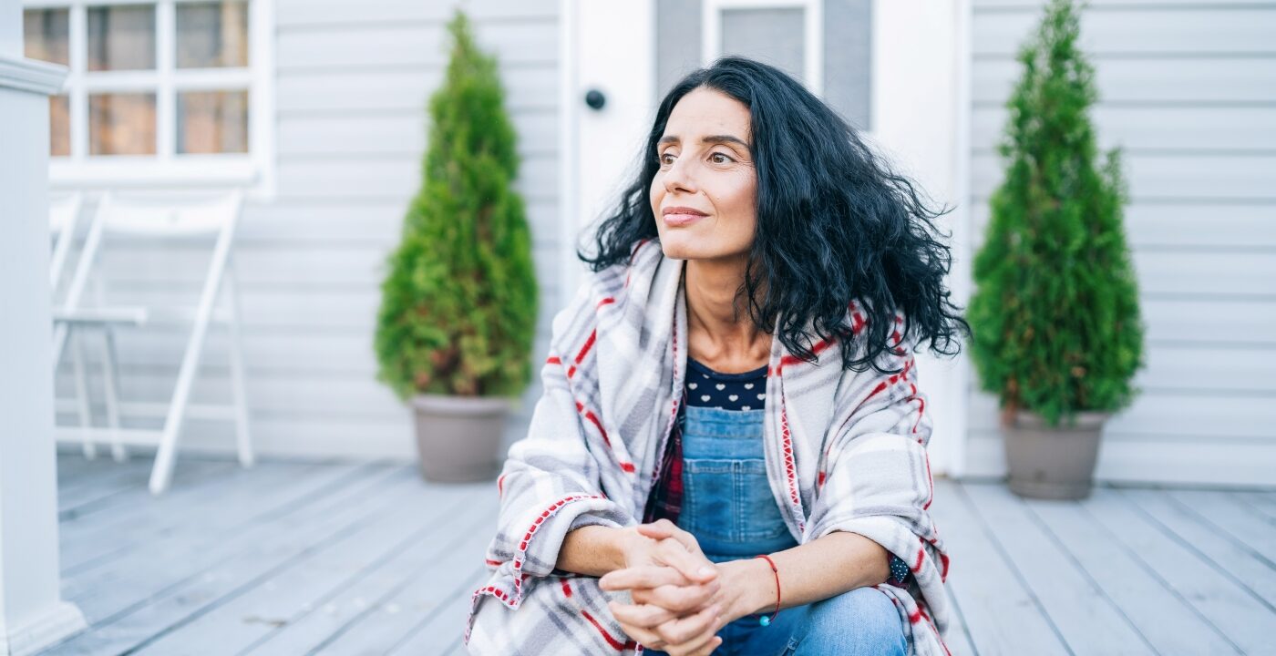 Woman sitting on porch wearing a plaid jacket