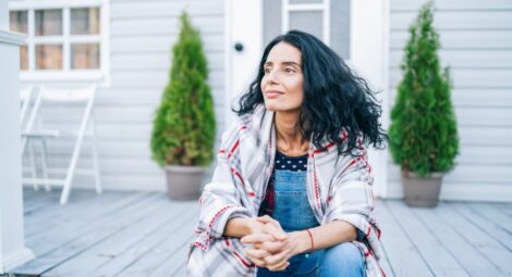 Woman sitting on porch wearing a plaid jacket