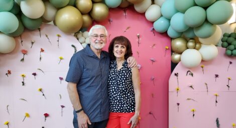 Man and woman stand underneath balloon arch
