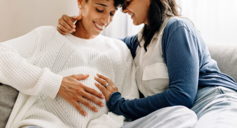 Two women smiling with hands on pregnant stomach