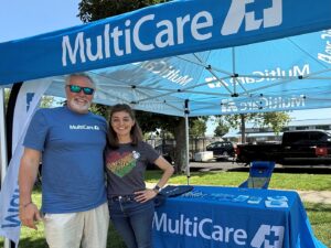 Yakima Juneteenth 2, Man and woman posing in front of booth, MultiCare Yakima region employees volunteer at the city’s Juneteenth celebration on June 14, 2025