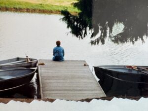 Person sitting on dock looking at water.