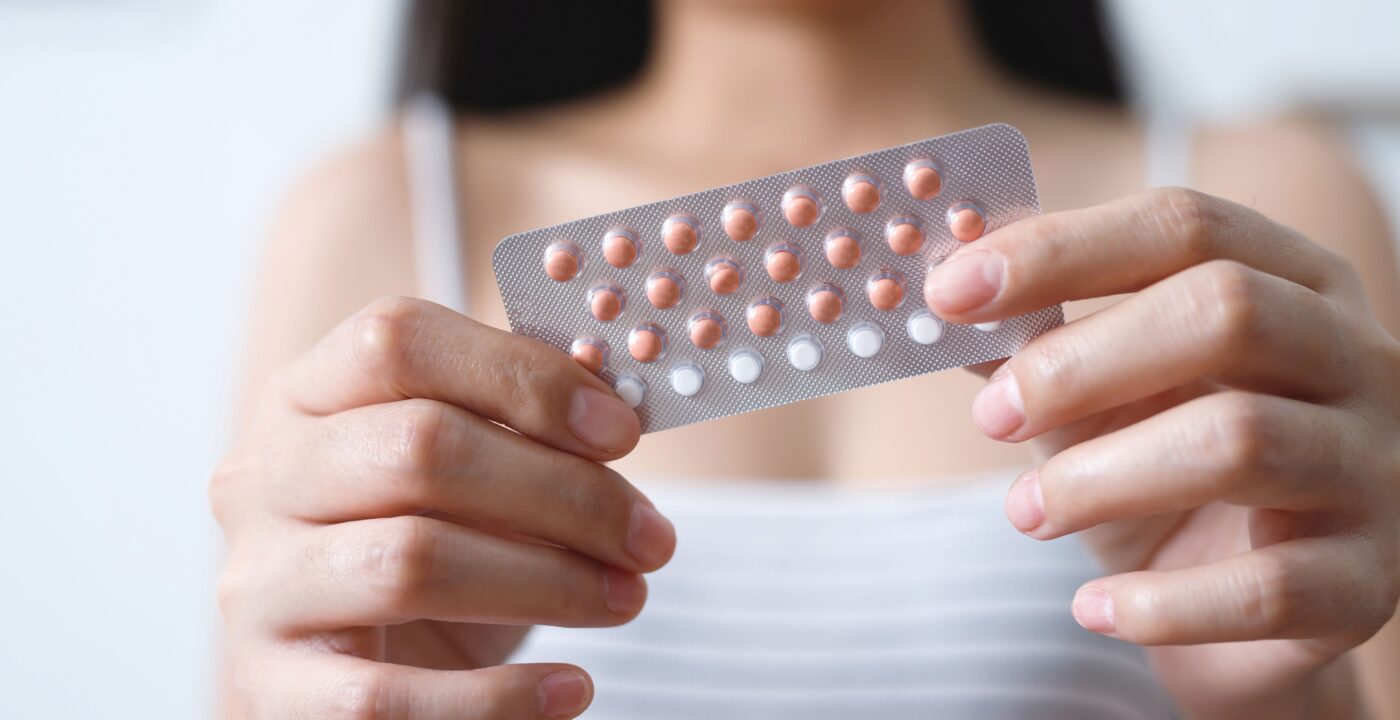 Young woman holding a pack of birth control pills