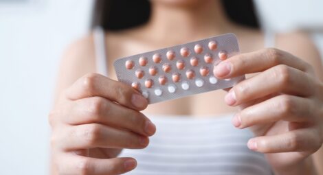 Young woman holding a pack of birth control pills