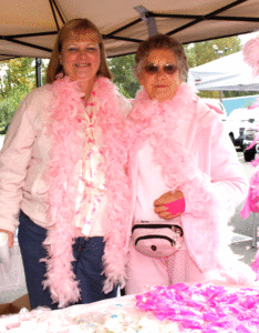Two women wearing pink boas