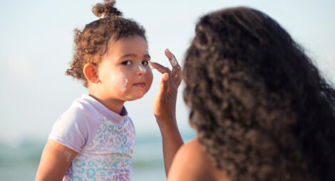 Mom applying sunscreen to child’s face on beach