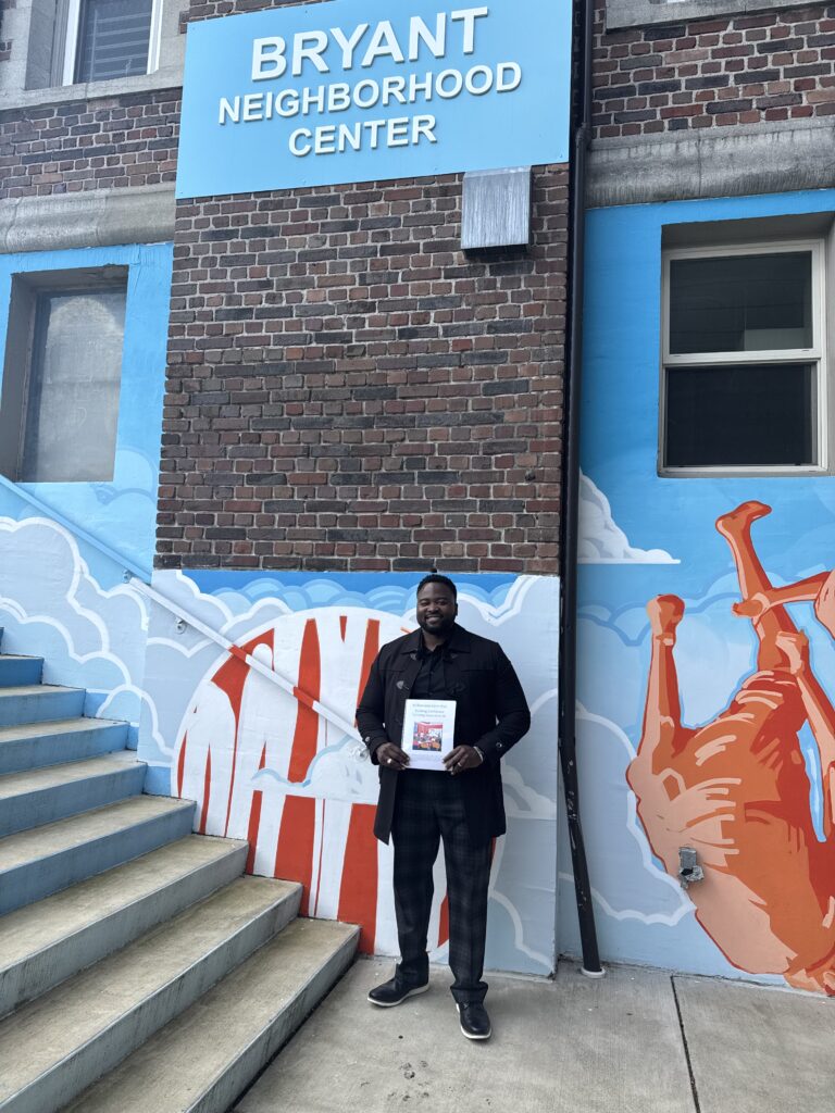 Man stands in front of building, Jermane Easterlin visited the Bryant Neighborhood Center as a child and now teaches classes at the Center.> 