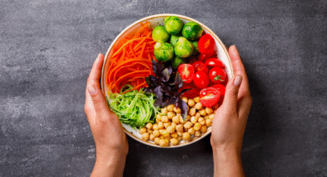 Hands wrapped around a bowl of fresh vegetables