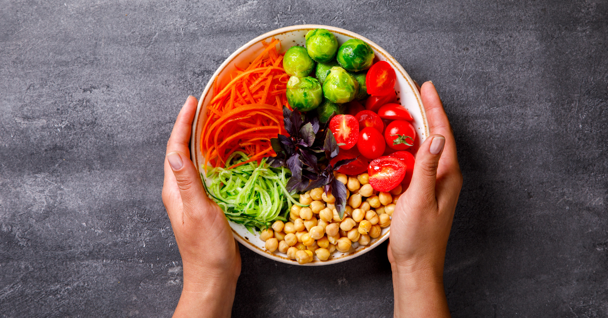 Hands wrapped around a bowl of fresh vegetables