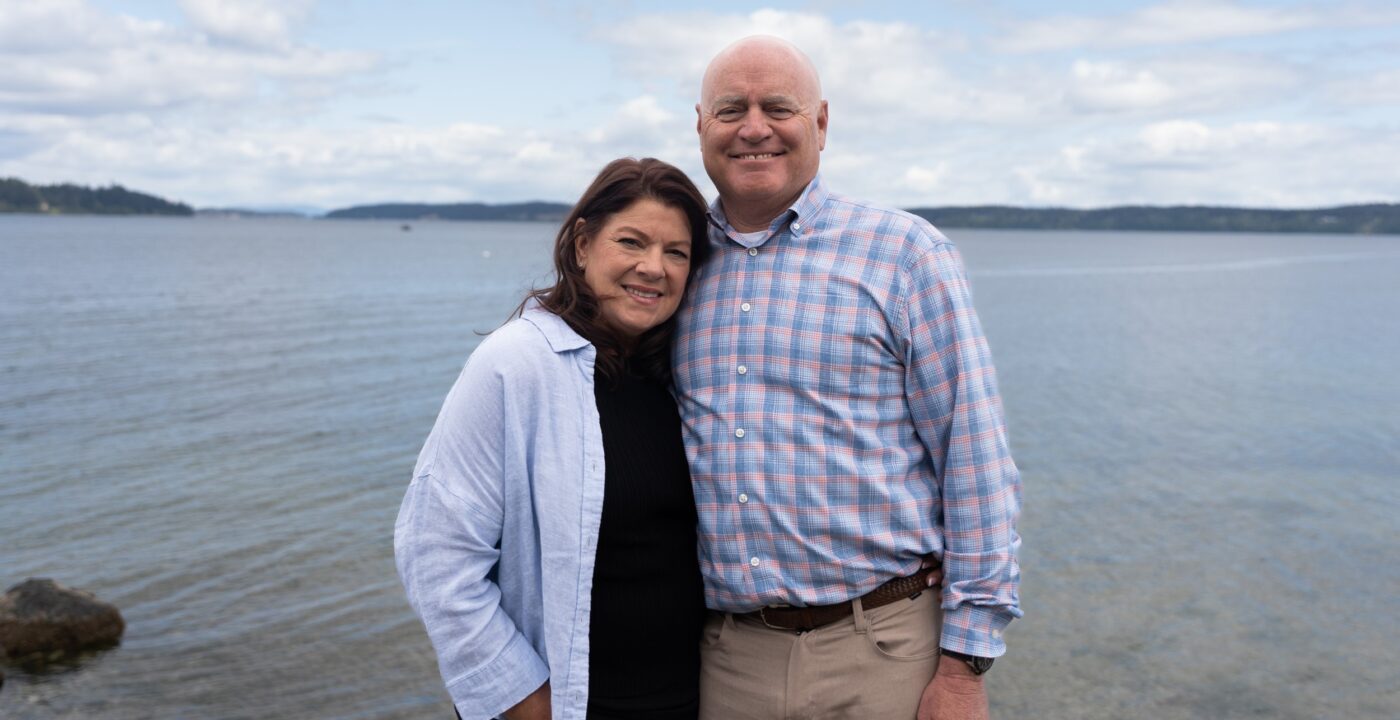 Man and woman smile for camera in front of the water