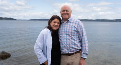 Man and woman smile for camera in front of the water