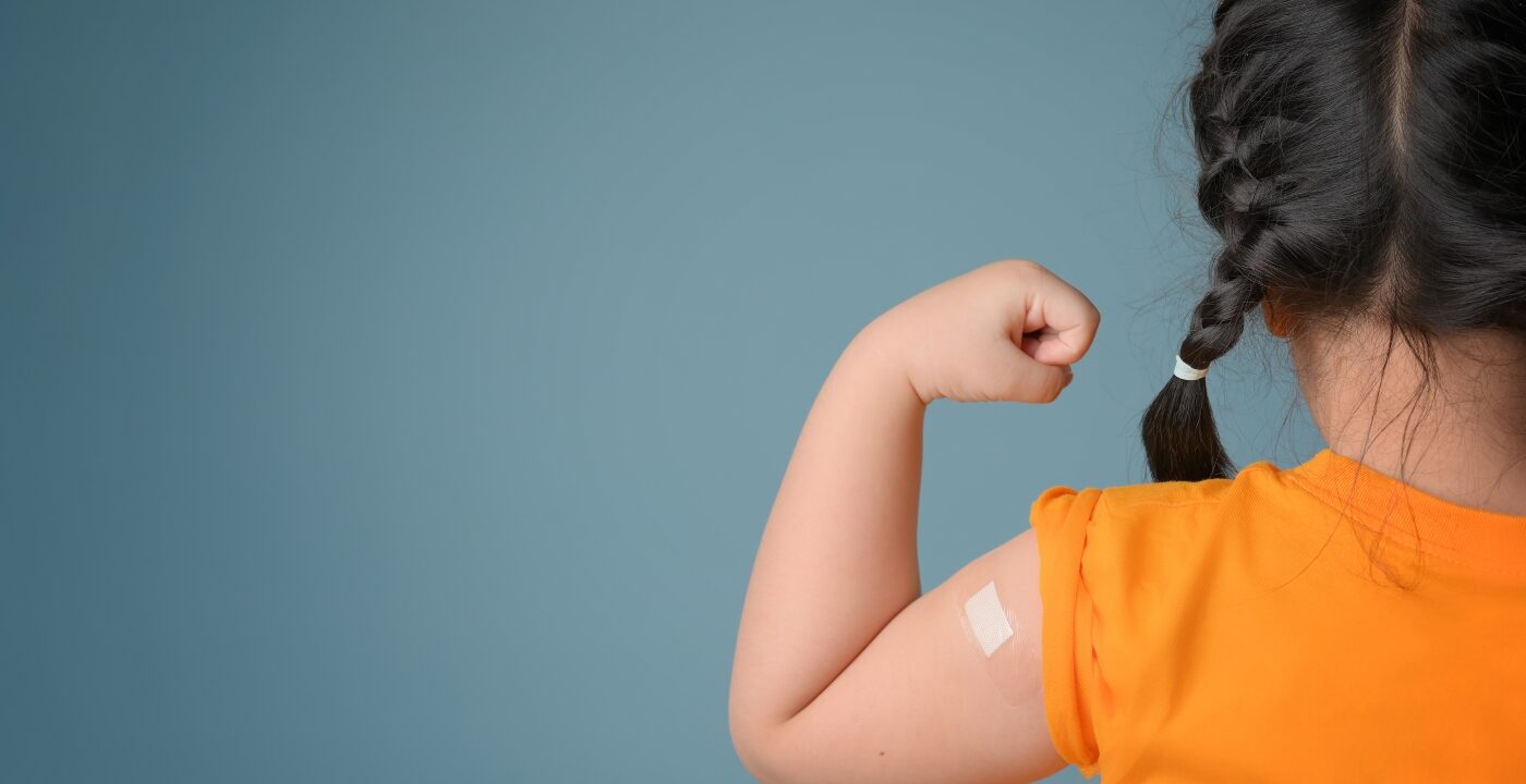 Little girl with bandage on her arm after receiving a vaccine