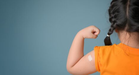 Little girl with bandage on her arm after receiving a vaccine