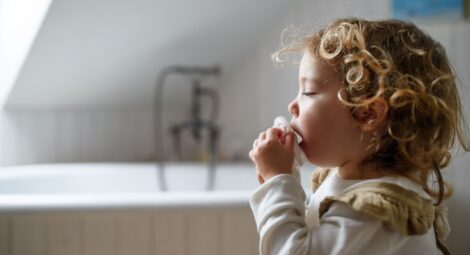 Sick toddler coughing into a tissue