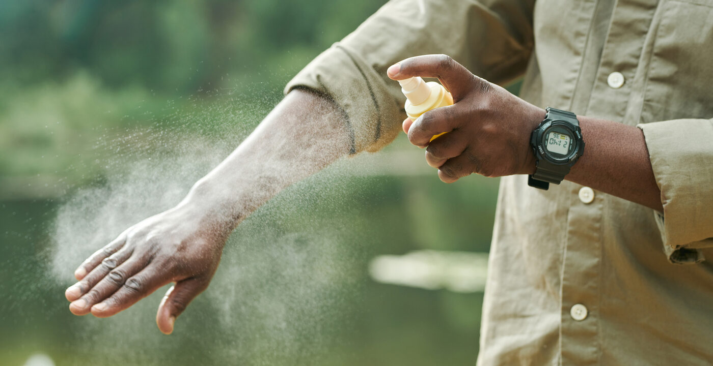 person spraying arm with bug spray