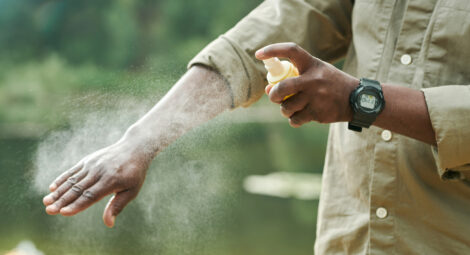 person spraying arm with bug spray