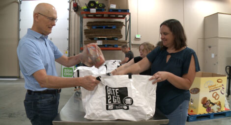 A man and woman pack food into a bag