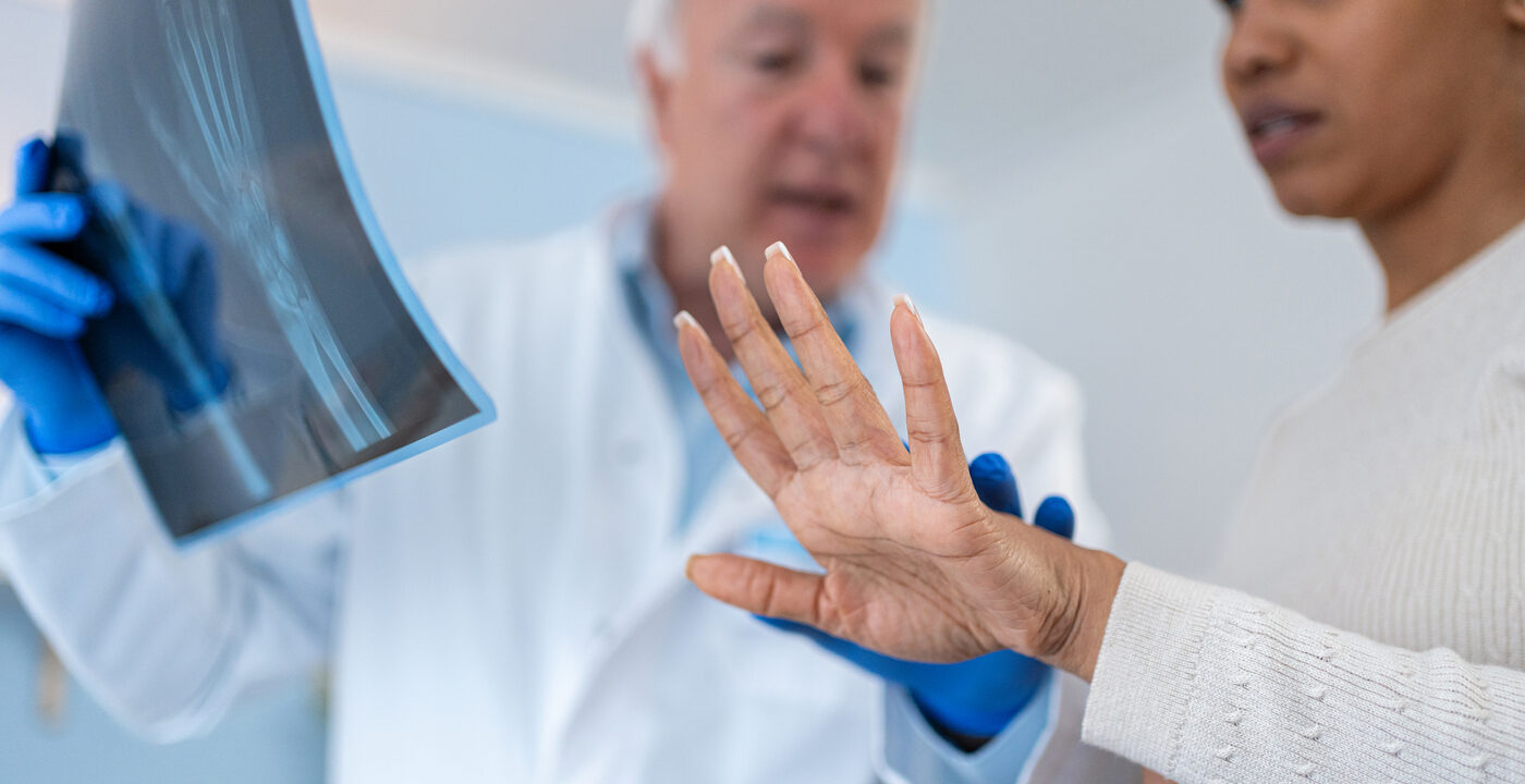 doctor holding X-ray of wrist as patient extends hand