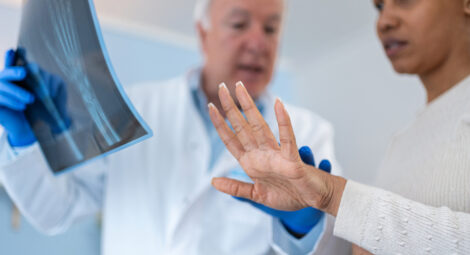 doctor holding X-ray of wrist as patient extends hand