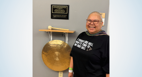 Woman stands next to gong