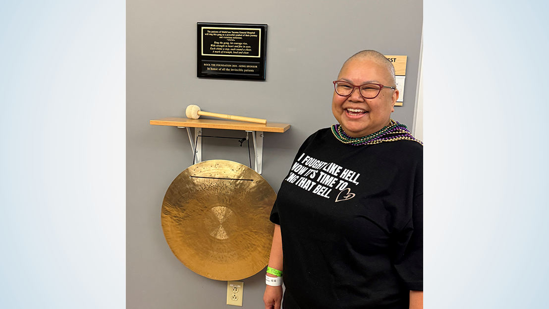 Woman stands next to gong