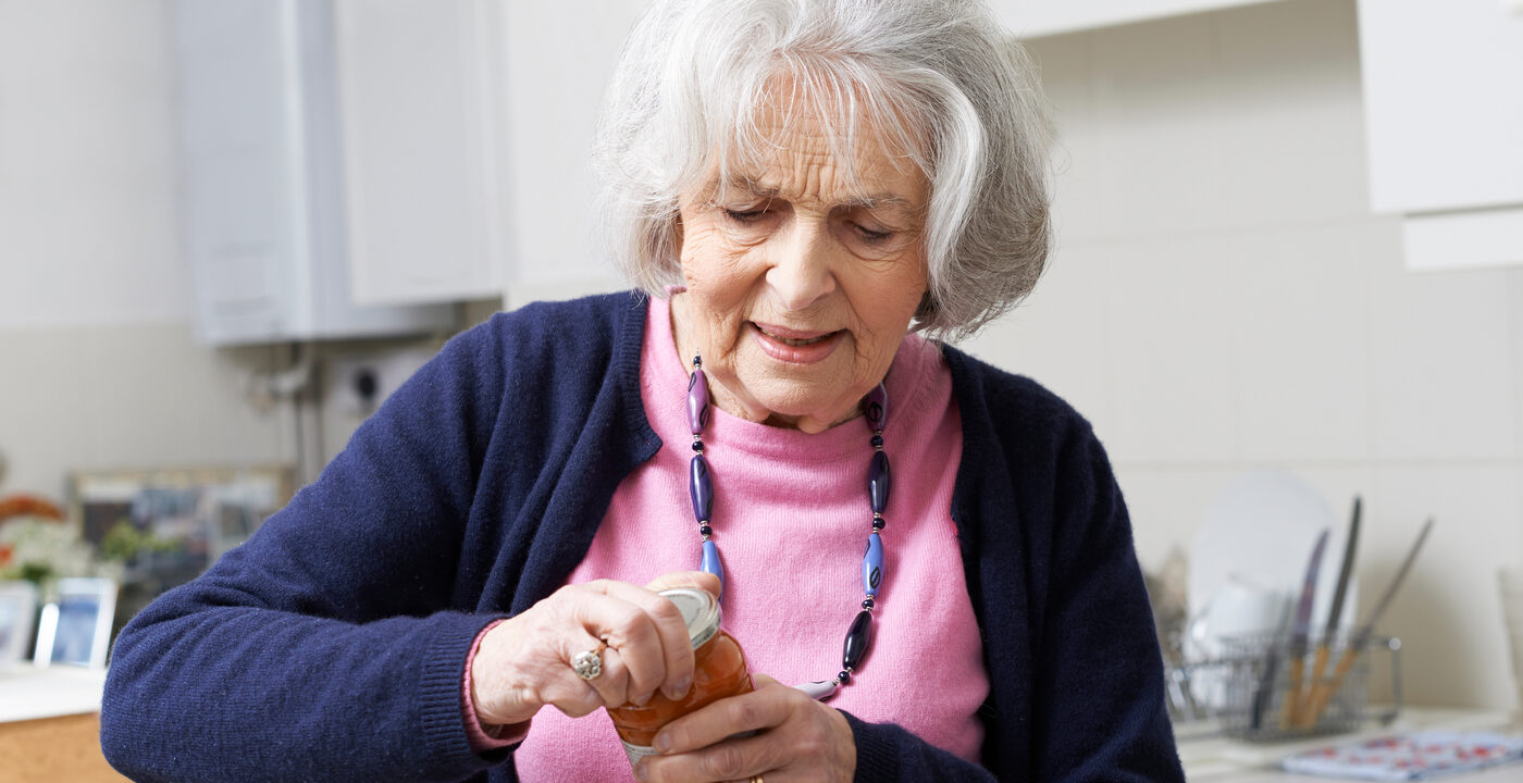 elderly woman struggling to open jar