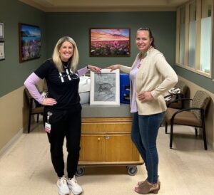 Two woman pose for photo, Crytall Ossello and Anissa McCrum pose for a photo with the newly donated CuddleCot