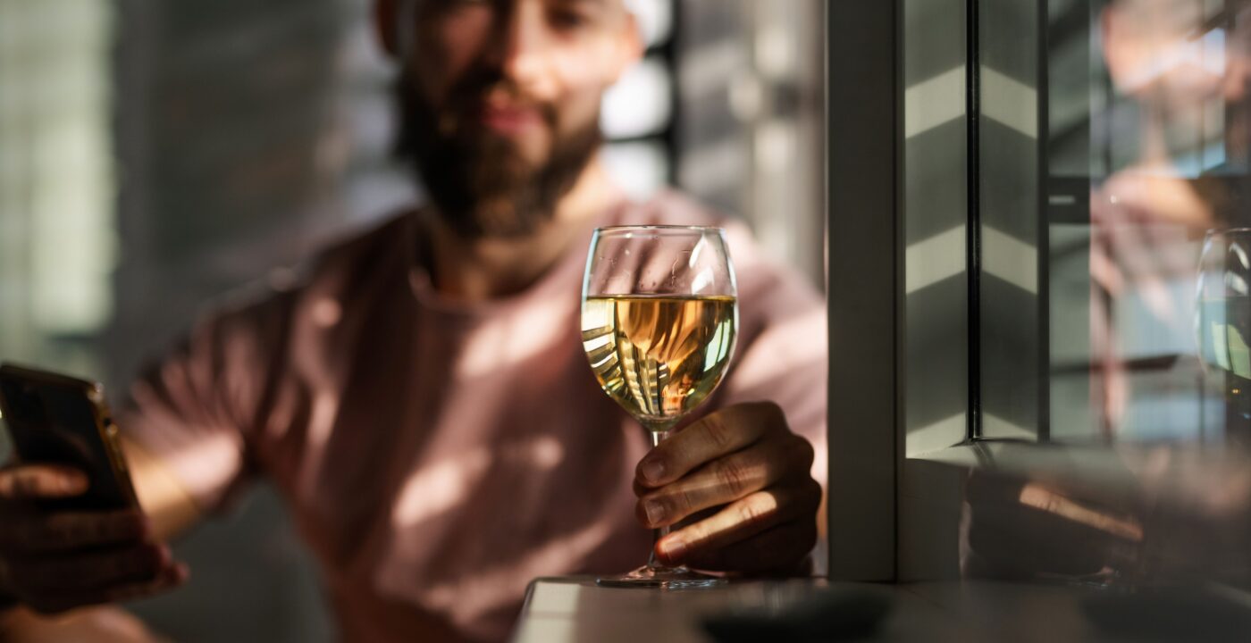 Man looking at a glass of white wine