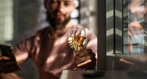 Man looking at a glass of white wine