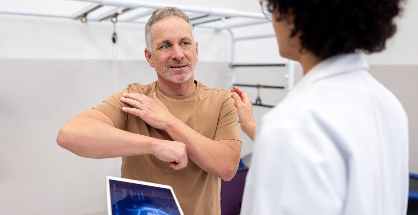 man shows doctor where shoulder hurts