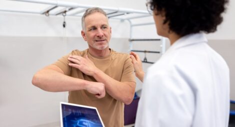 man shows doctor where shoulder hurts