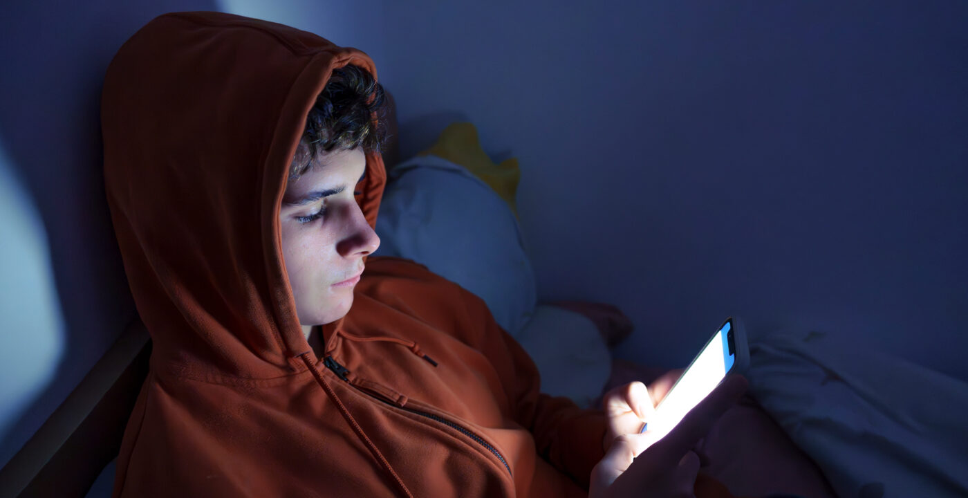 Boy in dark room on his phone