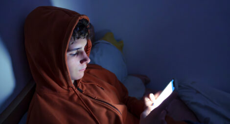 Boy in dark room on his phone