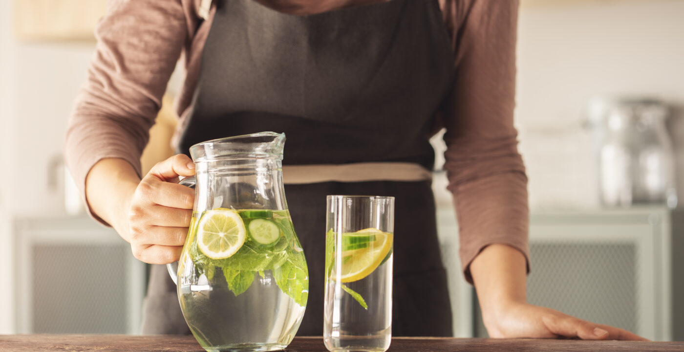 Lemon slices and mint leaves in pitcher and glass of water
