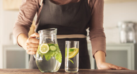 Lemon slices and mint leaves in pitcher and glass of water