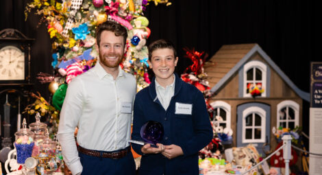 A young man stands next to a teenager holding an award.