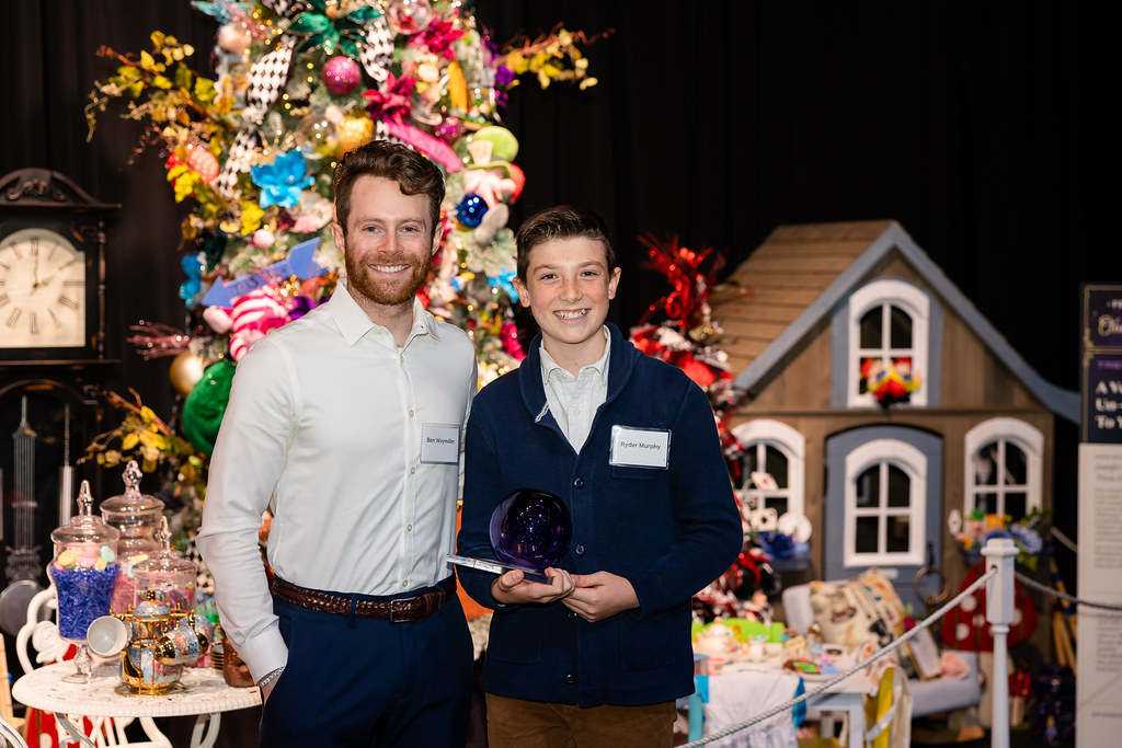 A young man stands next to a teenager holding an award.