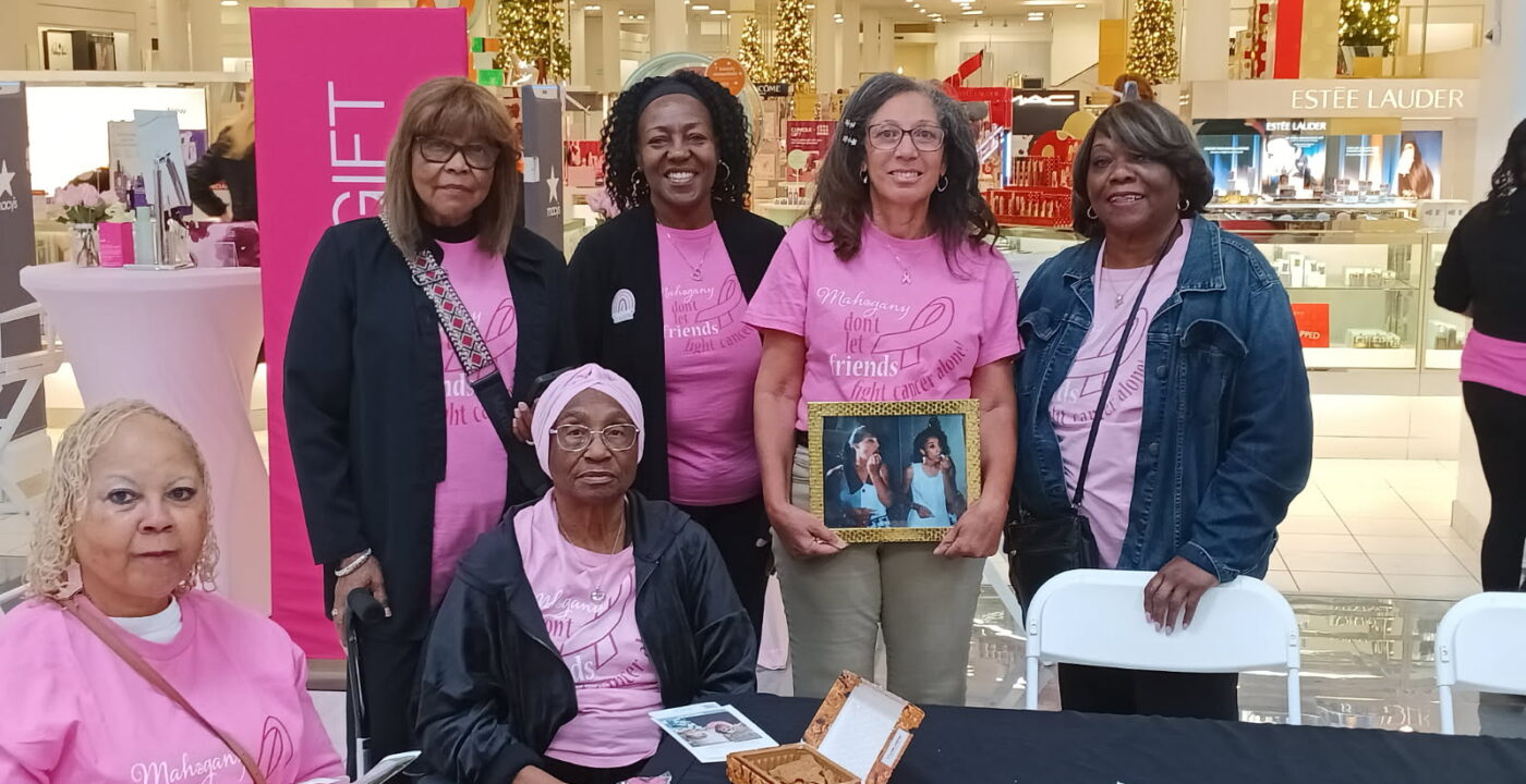 Women sitting at event table pose for photo